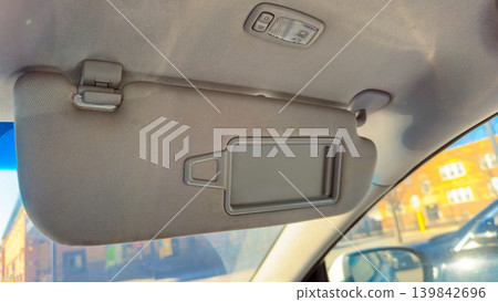 Car sun visor with a mirror set inside a vehicle showing part of the interior during daylight on a sunny day Car sun visor with a mirror set inside a vehicle showing part of the interior during daylight on a sunny day 139842696