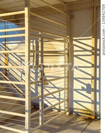 Metal gate and shadows show patterns on wall in a parking structure during the evening sunlight 139842709