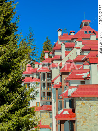 Red roof buildings surrounded by tall green trees under a clear blue sky during daytime in a mountainous area Red roof buildings surrounded by tall green trees under a clear blue sky during daytime in a mountainous area 139842725