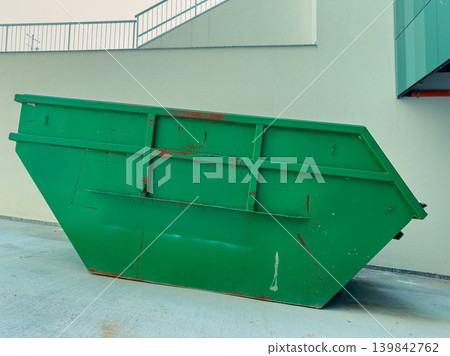 Large green dumpster placed beside a building on a concrete surface during daytime in an urban area Large green dumpster placed beside a building on a concrete surface during daytime in an urban area 139842762