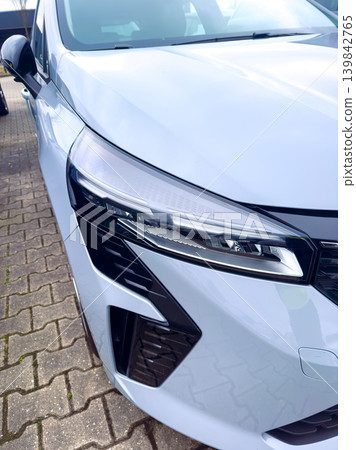 Car parked in a lot with a focus on the front design and headlights in bright daylight 139842765