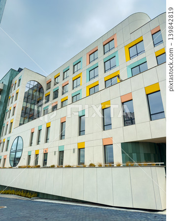 New modern building with colorful windows in a city setting during a cloudy day New modern building with colorful windows in a city setting during a cloudy day 139842819