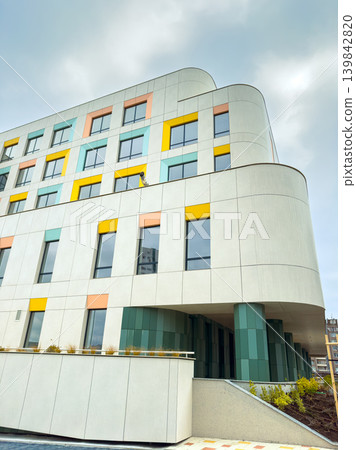 New modern building with colorful facade in an urban area seen during the day with visible clouds in the sky New modern building with colorful facade in an urban area seen during the day with visible clouds in the sky 139842820