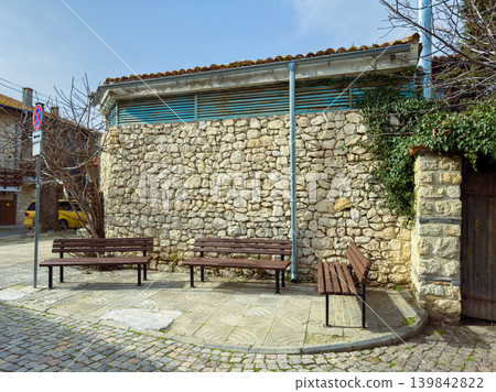 Outdoor seating area with benches near stone wall in quiet neighborhood during daytime in an urban setting 139842822
