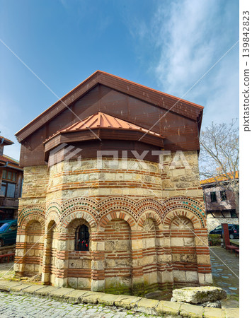 Old stone building located in a village square with a metal roof and brick decoration during the day in springtime Old stone building located in a village square with a metal roof and brick decoration during the day in springtime 139842823