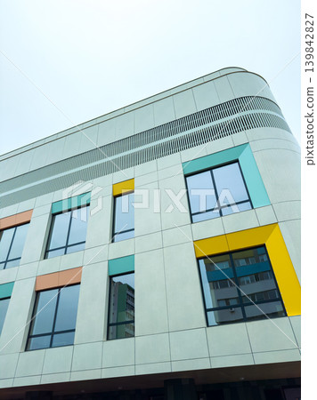 Modern building with colorful windows in an urban area during a cloudy day Modern building with colorful windows in an urban area during a cloudy day 139842827