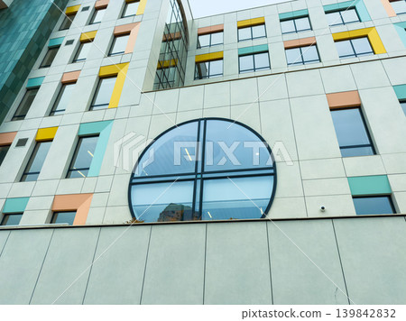 Building with round window in a modern neighborhood showing colorful design elements on a cloudy day Building with round window in a modern neighborhood showing colorful design elements on a cloudy day 139842832
