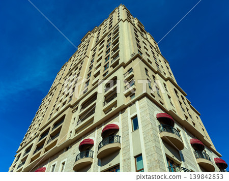 Tall building with red balconies under blue sky in a city during daylight showing urban design and architecture 139842853