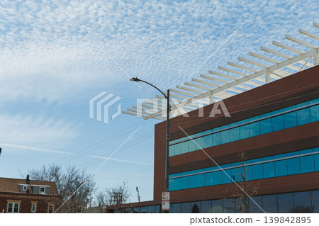 Building with glass windows under a blue sky with clouds seen from street level during daytime in a city Building with glass windows under a blue sky with clouds seen from street level during daytime in a city 139842895