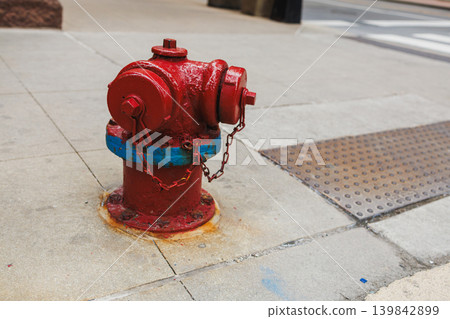 Fire hydrant stands on sidewalk in urban area near street during daytime in city setting Fire hydrant stands on sidewalk in urban area near street during daytime in city setting 139842899