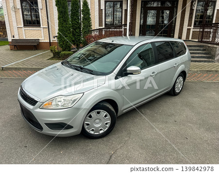Silver car parked in front of a building with trees and steps in a city area during the day Silver car parked in front of a building with trees and steps in a city area during the day 139842978