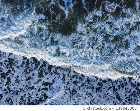 Waves break on the shore during the afternoon at a beach with white sand and blue water Waves break on the shore during the afternoon at a beach with white sand and blue water 139843008