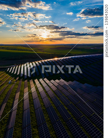 Solar panels cover fields in a renewable energy facility during sunset in a rural area, showcasing modern energy solutions and agricultural land Solar panels cover fields in a renewable energy facility during sunset in a rural area, showcasing modern energy solutions and agricultural land 139843020