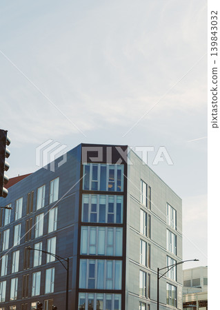 Building with modern design stands tall under the blue sky in an urban setting during the day, showcasing glass and steel elements along a busy street Building with modern design stands tall under the blue sky in an urban setting during the day, showcasing glass and steel elements along a busy street 139843032