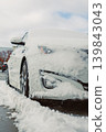 Snow covers a parked car in a city parking lot during winter on a cloudy day 139843043