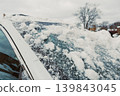 Snow covers the roof of a car in a residential area on a cloudy winter day 139843045