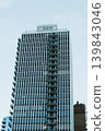 Tall building with many floors and balconies located in a city under a clear blue sky during the day time with some lights turning on in the windows 139843046