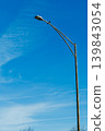 Bird resting on a street lamp under a clear blue sky during the day 139843054