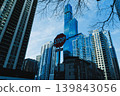 Tall buildings rise against the sky with a stop sign visible in the foreground during daylight in an urban city setting 139843056