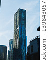 Tall building with a unique design stands against a bright sky in an urban area during the daytime 139843057