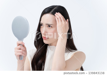 一位女士對著手鏡檢查自己的髮際線。 139843138