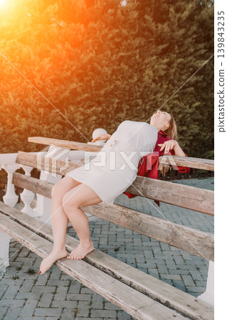 Woman park laughing leaning back on wooden park bench during sunset in carefree joy 139843235