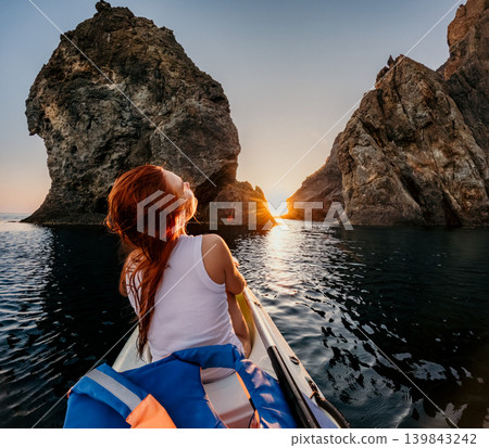 Kayak sunset woman rows her boat through narrow passage between rocks at sea enjoying a tranquil evening under warm golden hour light Kayak sunset woman rows her boat through narrow passage between rocks at sea enjoying a tranquil evening under warm golden hour light 139843242