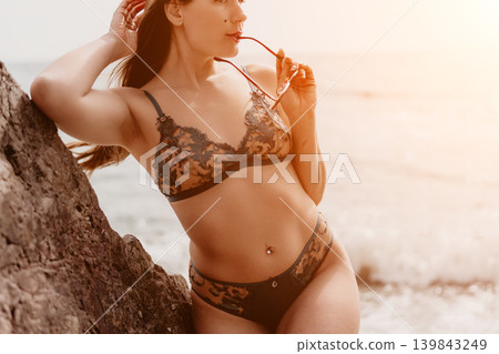 Lingerie Woman Coast Attractive woman in lace underwear posing against a rock on a sunny beach with ocean waves in background Lingerie Woman Coast Attractive woman in lace underwear posing against a rock on a sunny beach with ocean waves in background 139843249