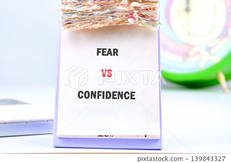 A white desk calendar displays the powerful words Fear vs Confidence in bold text A white desk calendar displays the powerful words Fear vs Confidence in bold text 139843327