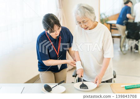 職能治療師和女性護理經理使用烹飪用具幫助老年女性進行復健。 職能治療師和女性護理經理使用烹飪用具幫助老年女性進行復健。 139843708