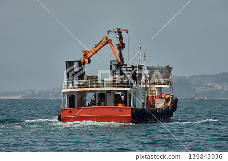 Traditional Galician mussel harvesting with an orange mussel boat off the coast of Vigo Traditional Galician mussel harvesting with an orange mussel boat off the coast of Vigo 139843936