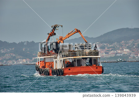 Traditional Galician mussel harvesting with an orange mussel boat off the coast of Vigo 139843939