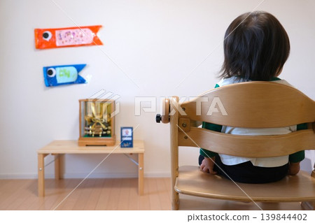A doll for the Boys' Festival displayed in the room, a handmade carp streamer, and the back view of a toddler. 139844402
