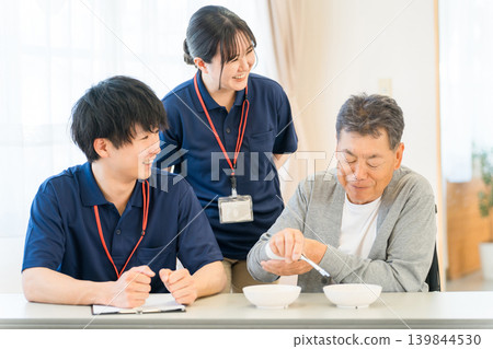 Male patients and male and female caregivers doing bean-grabbing training at nursing homes, hospitals, and rehabilitation centers Male patients and male and female caregivers doing bean-grabbing training at nursing homes, hospitals, and rehabilitation centers 139844530
