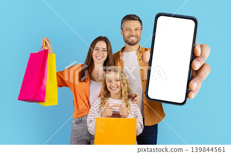 Smiling caucasian family with shopping bags showing blank smartphone screen 139844561