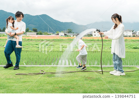 A family watering the lawn in their garden (home, garden, exterior) A family watering the lawn in their garden (home, garden, exterior) 139844751
