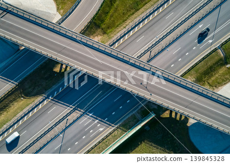 Aerial view of a multi-level highway interchange with a bridge crossing several roads. Cars drive during the bright sunny day 139845328