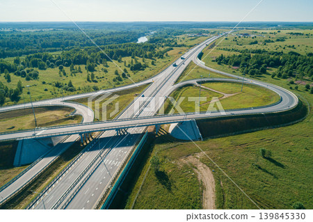 Modern highway interchange featuring multiple lanes and bridges in a vast green rural landscape during a bright sunny day 139845330