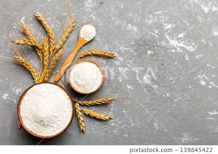 Flat lay of Wheat flour in wooden bowl with wheat spikelets on colored background. world wheat crisis 139845422