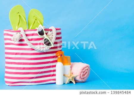 Stylish bag with beach accessories . Summer holiday concept. Top view of beach bag with sunscreen cream with space for text Stylish bag with beach accessories . Summer holiday concept. Top view of beach bag with sunscreen cream with space for text 139845484