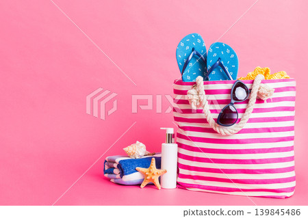 Stylish bag with beach accessories . Summer holiday concept. Top view of beach bag with sunscreen cream with space for text Stylish bag with beach accessories . Summer holiday concept. Top view of beach bag with sunscreen cream with space for text 139845486