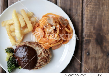 A plate of hamburger steak with demi-glace sauce, potatoes, and Neapolitan spaghetti. A plate of hamburger steak with demi-glace sauce, potatoes, and Neapolitan spaghetti. 139845560