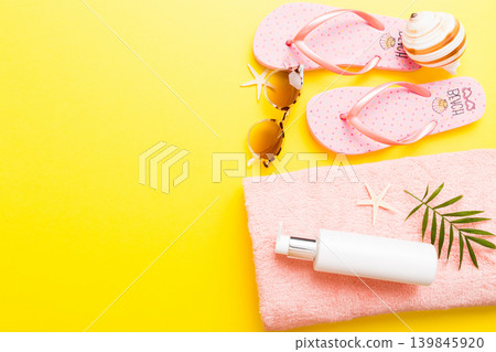 Summer holiday concept. Top view of beach towel, flip flop and sunscreen cream on table Top view with copy space for text Summer holiday concept. Top view of beach towel, flip flop and sunscreen cream on table Top view with copy space for text 139845920
