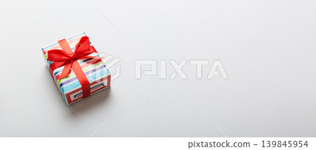Wrapped christmas or other holiday handmade present in paper with colored ribbon. Present box, decoration of gift on table, top view with copy space Wrapped christmas or other holiday handmade present in paper with colored ribbon. Present box, decoration of gift on table, top view with copy space 139845954