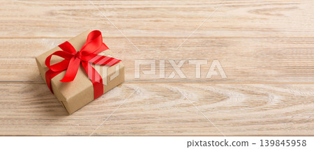 Wrapped christmas or other holiday handmade present in craft paper with colored ribbon. Present box, decoration of gift on table, top view with copy space Wrapped christmas or other holiday handmade present in craft paper with colored ribbon. Present box, decoration of gift on table, top view with copy space 139845958