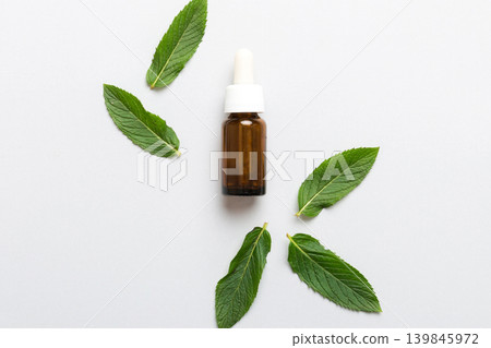 Natural Mint Essential Oil in a Glass Bottle. organic cosmetics with herbal extracts of mint on colored background Natural Mint Essential Oil in a Glass Bottle. organic cosmetics with herbal extracts of mint on colored background 139845972