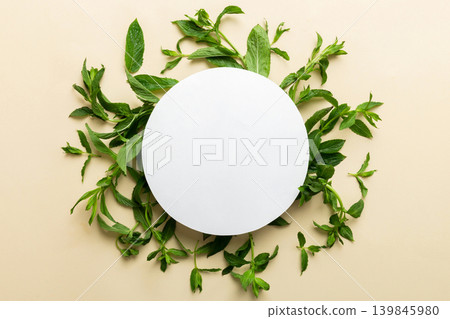 Wreath frame made of empty paper blank with space for text and mint leaves on colored background. . Mint Pattern. Flat lay. Top view Wreath frame made of empty paper blank with space for text and mint leaves on colored background. . Mint Pattern. Flat lay. Top view 139845980