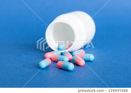 plastic medicine bottle with capsules of pills on colored background. Online pharmacy. Painkiller medicine and antibiotic drug resistance concept. Pharmaceutical industry plastic medicine bottle with capsules of pills on colored background. Online pharmacy. Painkiller medicine and antibiotic drug resistance concept. Pharmaceutical industry 139845986