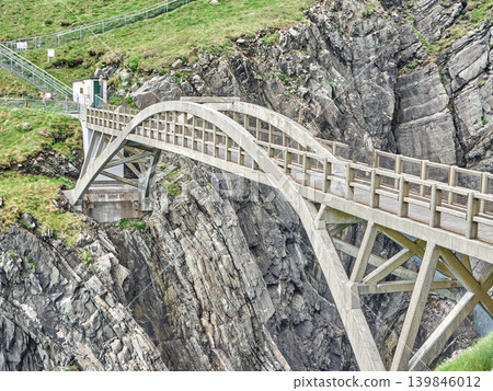 Concrete arch bridge over rocky coastal cliff 139846012