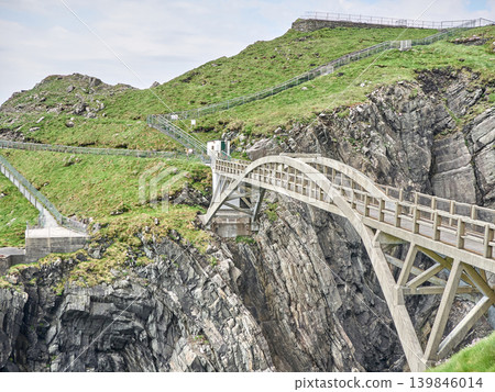 Suspension bridge crossing rugged coastal cliffs Suspension bridge crossing rugged coastal cliffs 139846014